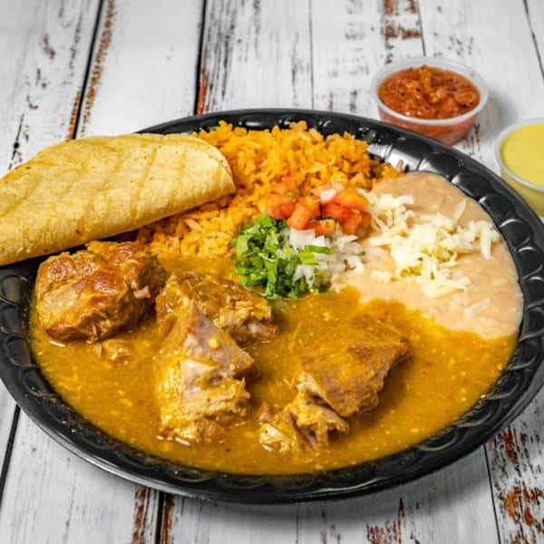 Bandeño Mexican Food's pork in green sauce with rice, beans, and a tortilla on a black plate.